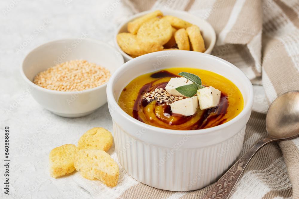 Pumpkin soup puree with sauce, soy cheese and sesame seeds and toasts in a white bowl on a light table napkin Pumpkin soup puree with sauce, soy cheese and sesame seeds and toasts in a white bowl on a light table napkin