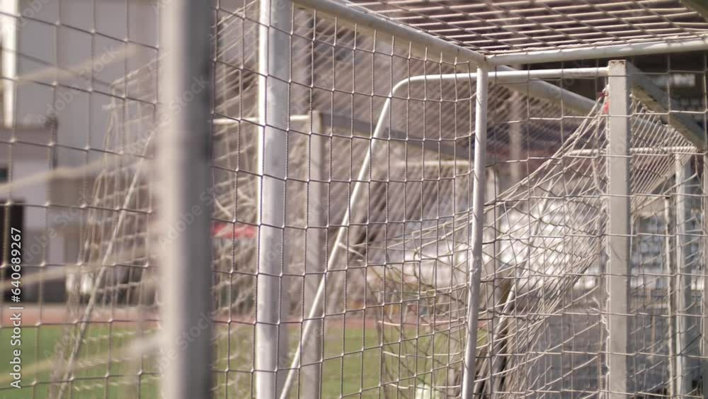 Low angle view of net. A slow motion shot of a football goal in sunlight. Low angle view of net. A slow motion shot of a football goal in sunlight.