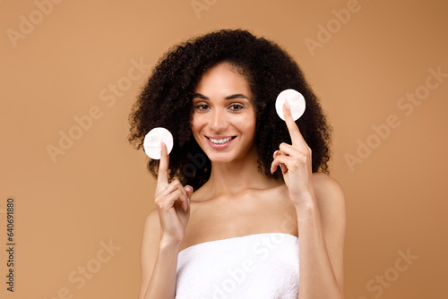Skincare routine. Beautiful latin lady holding two cotton pads and smiling, enjoying daily beauty care