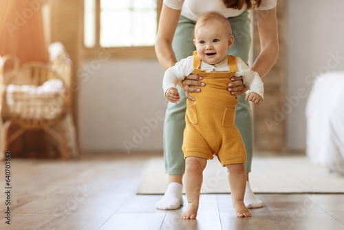 Fotografia Happy baby boy making first steps in home with mother