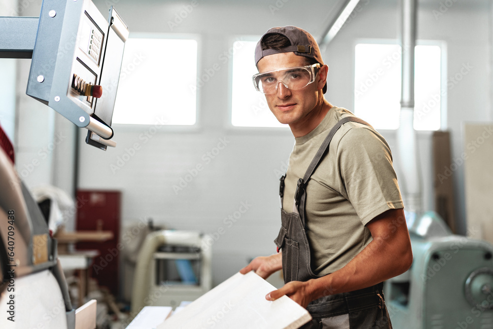 Fototapeta premium Male carpenter using some woodworking tools for his work in a factory