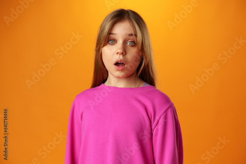 Surprised amazed teen girl against yellow background in studio