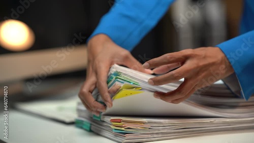 Businessman man working in stacks of papers searching for unfinished paperwork information on form check stack on table and checking financial papers in busy workload