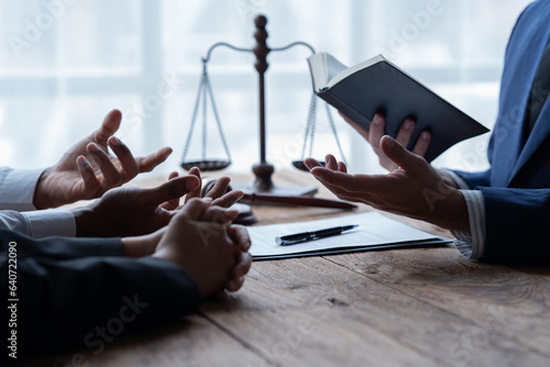 The lawyer sitting at desk with scales of justice, gavel and small wooden house, working with documents, signing contract agreements. Real estate law, foreclosed property, lawyer services concept