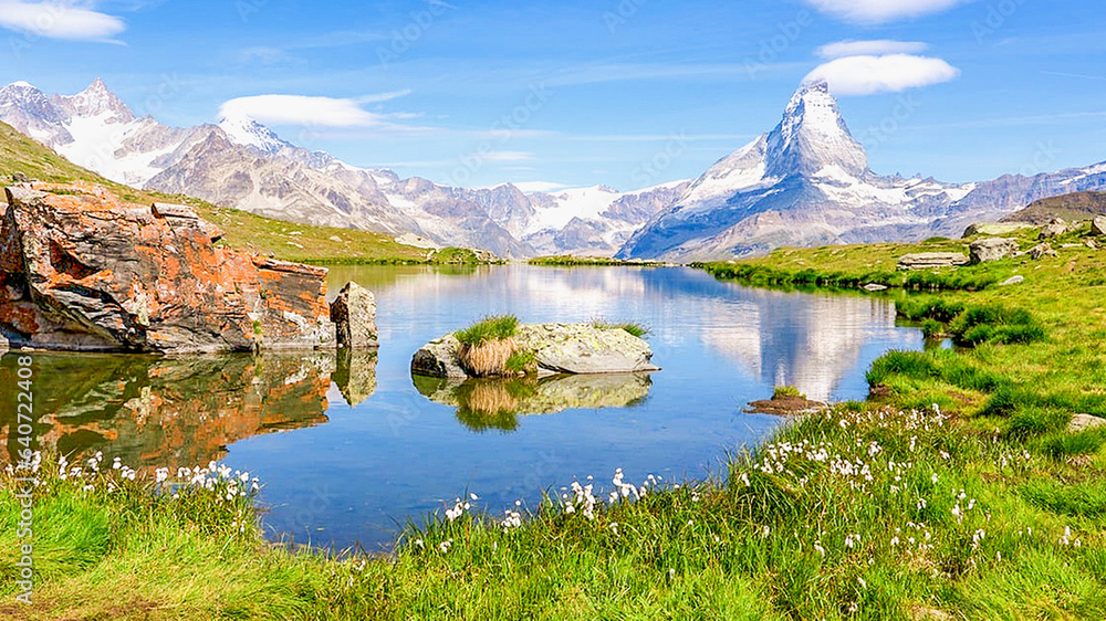 Souvenir de randonnée en altitude dans les Alpes avec un petit lac d'alpage en montagne avec le reflet des sommets enneigés en d'altitude