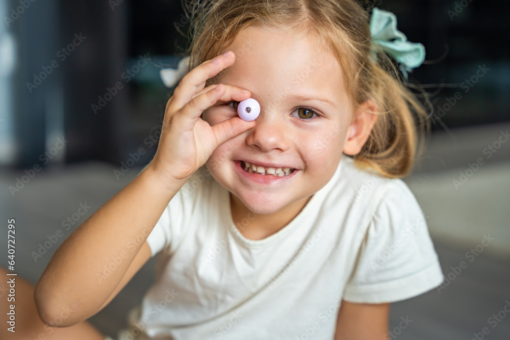 Little girl plays with bead making wooden beads bracelet. Children's creativity and the development of fine motor skills Little girl plays with bead making wooden beads bracelet. Children's creativity and the development of fine motor skills
