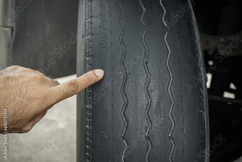 Close-up of man\'s hand pointing at old worn and bald tires from use. concept of tire wear and the dangers of using old tires.