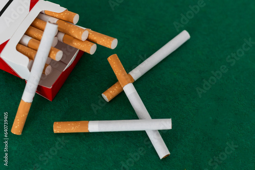  A pile of cigarettes scattered, green background. 