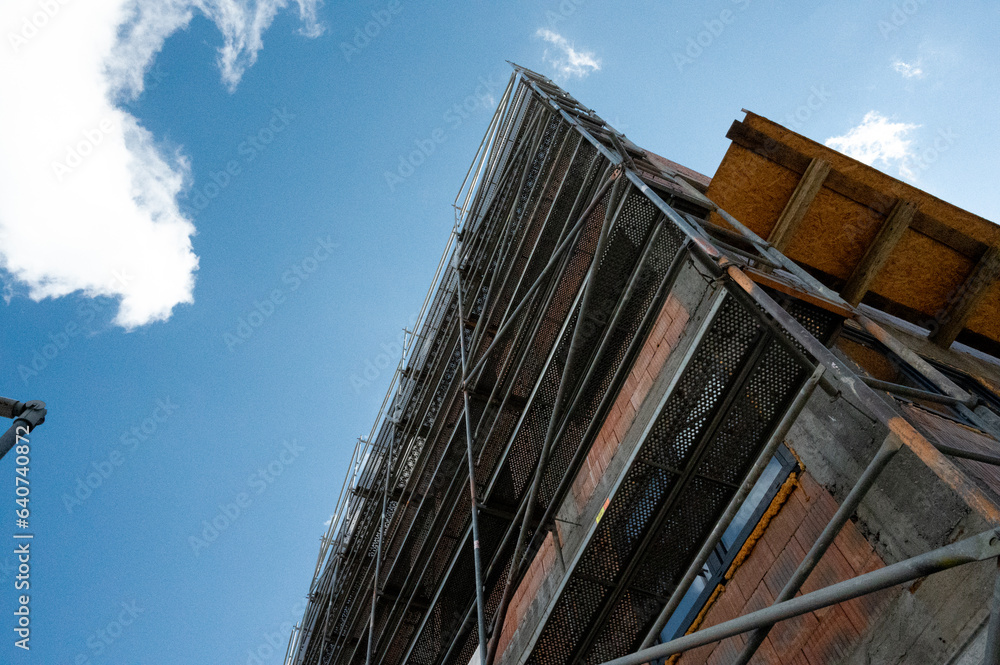 Obraz premium Scaffolding on multi storey building facade during facade renovation. Bright sunny day.