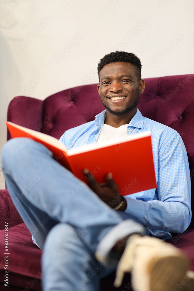 A content young man reading a book at home, immersed in education and relaxation.