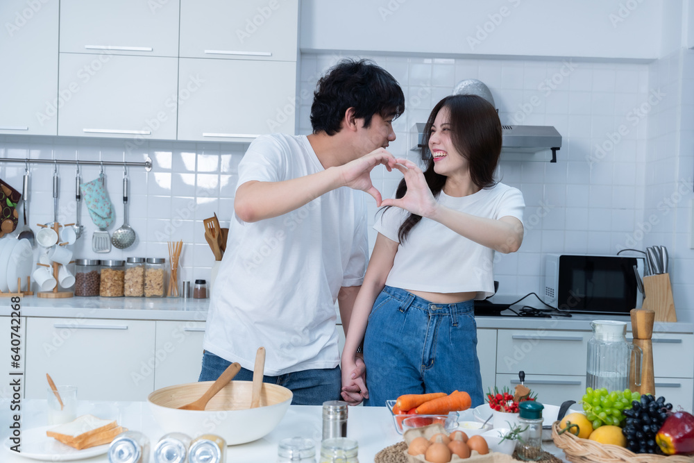 Happy portrait of loving young asian of having fun standing a cheerful heart shaped hands preparing food and enjoy cook cooking bread while standing on a kitchen Condo life or home Happy portrait of loving young asian of having fun standing a cheerful heart shaped hands preparing food and enjoy cook cooking bread while standing on a kitchen Condo life or home