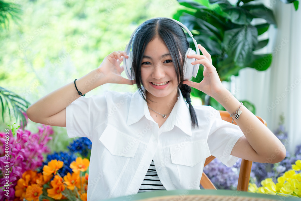 Happy of cute smiles Asian of attractive young Cute little girl wearing white wireless headphones and listening music enjoying favourite audio at the cafe on vacation at a coffee shop.