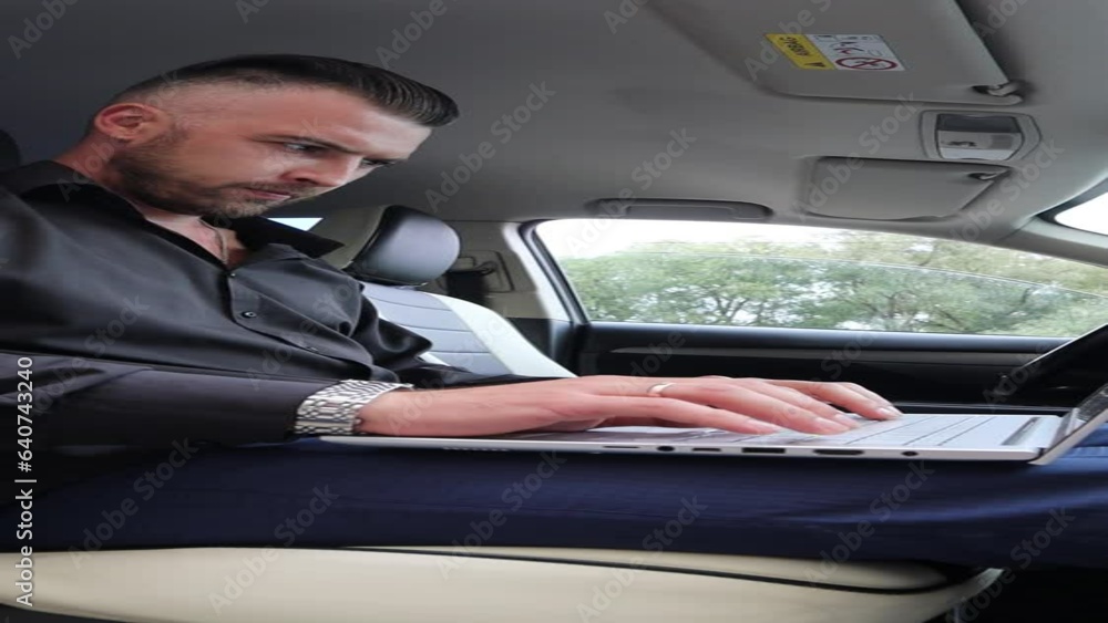 A man in a black shirt is sitting in his car working on his laptop. High quality video A man in a black shirt is sitting in his car working on his laptop. High quality video