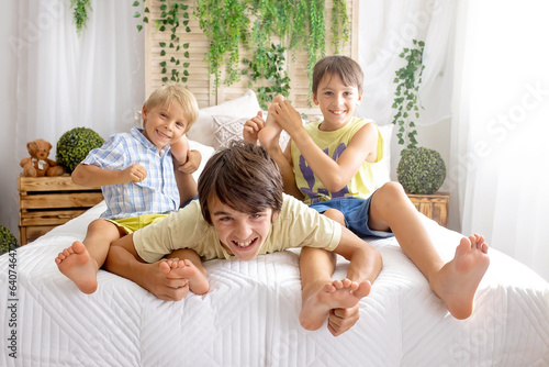 Happy positive children, tickling on the feet, having fun together, boy brothers at home having wonderful day of joy photo