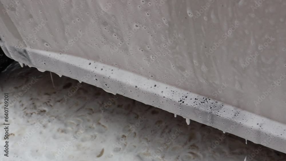 Cleaning the car with foam. White, thick foam runs down the car door Cleaning the car with foam. White, thick foam runs down the car door