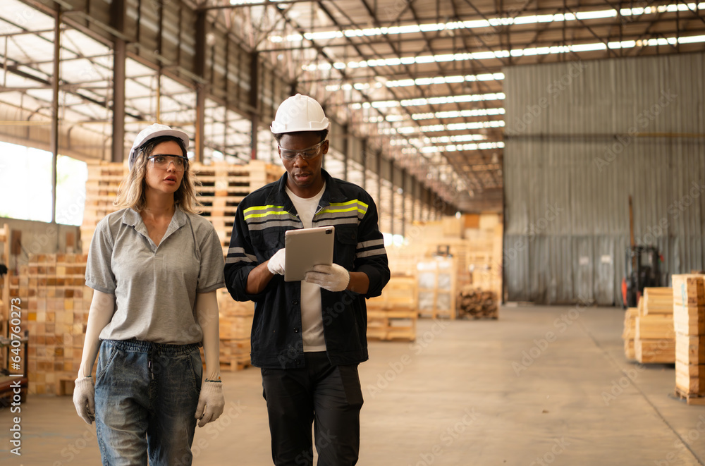Front view of diverse female and male warehouse workers using digital tablet for working in wooden factory. Front view of diverse female and male warehouse workers using digital tablet for working in wooden factory.