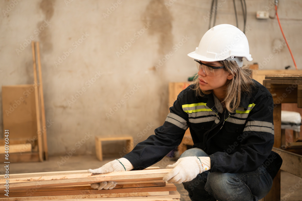 A carpenter works in a carpentry workshop. She collects the wood that passes through the wood angle grinder.