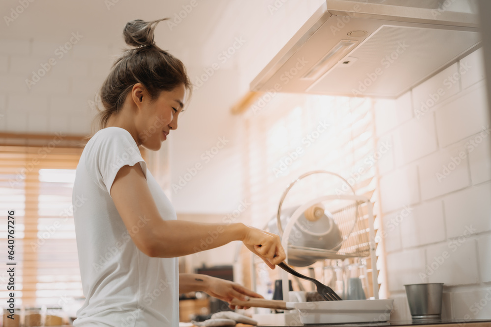 Asian woman in white t-shirt cooking in the kitchen making lunch.