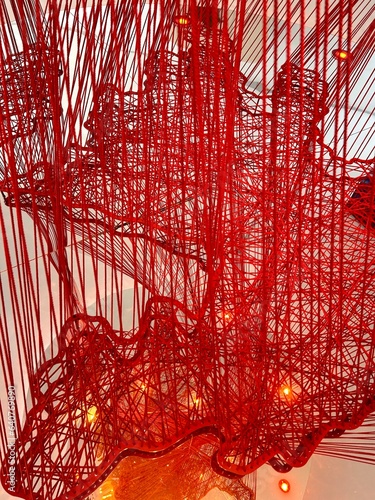 Art object. Decorative element. Wall decoration. Red thread background. Red thread interweaving. Complex interweaving of fibers. Network net yarn. Abstract backdrop.