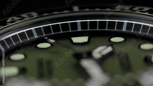Extreme closeup second arrow passing by on clock face. Running second arrow. Closeup view of rotating luxury sports watch. Green clock face, diving watch, military watches