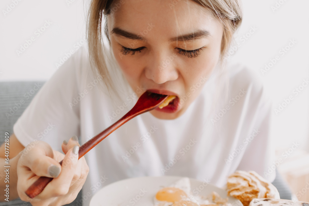 Funny face of asian woman putting breakfast into her mouth. Concept of dietary. Funny face of asian woman putting breakfast into her mouth. Concept of dietary.