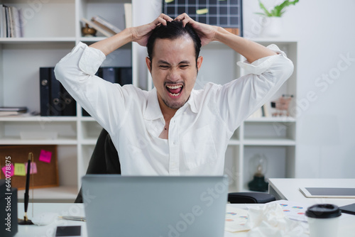 The overworked businessman or manager, grapples with frustration and anger in the office. A throbbing headache worsens as deadlines loom, intensifying the problem. Exhausted, overwhelmed and screaming photo