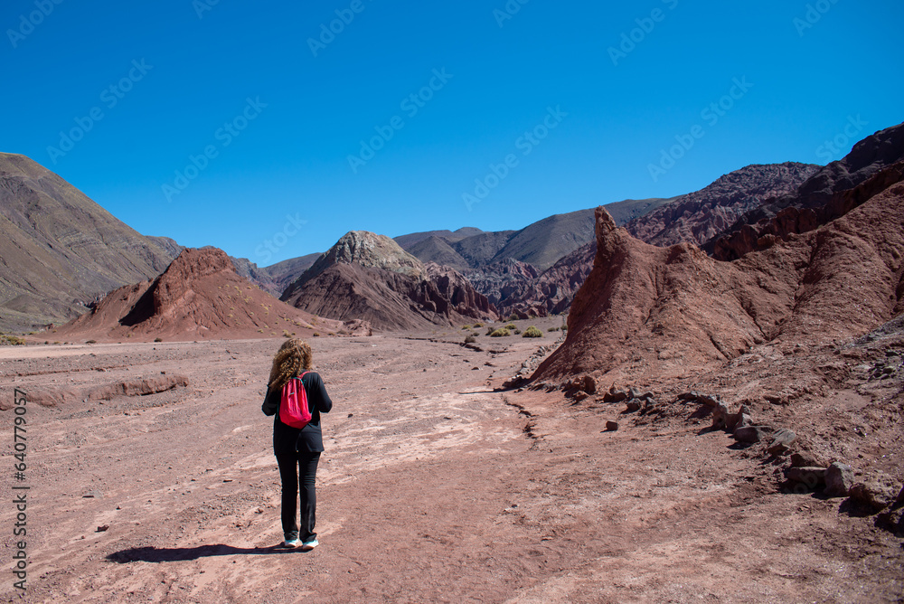 woman with red backpack walking trough valle arcoiris, antofagasta, atacama, chile