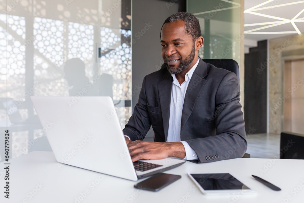 Successful mature african american businessman at work inside office, experienced boss working with laptop, man smiling satisfied with achievement results. Successful mature african american businessman at work inside office, experienced boss working with laptop, man smiling satisfied with achievement results.
