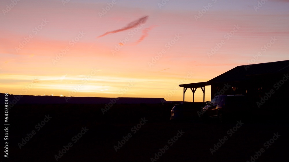 sunset over the Grand Canyon at the distance with a cabin and the foreground in silhouette