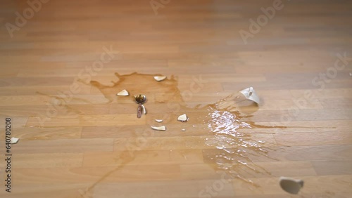 A cup of tea falls and breaks on the floor. Slow motion