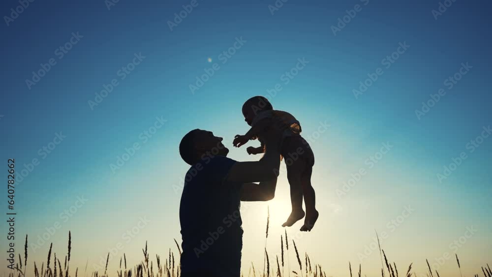 father throws play baby in the park. father's day silhouette happy