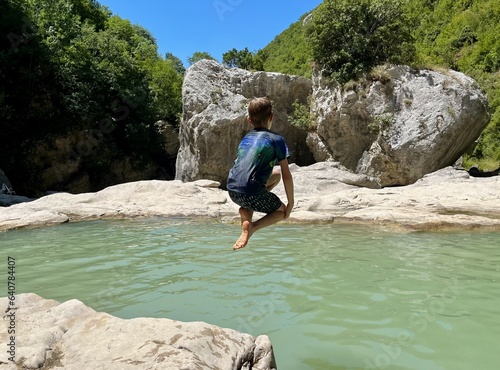 Boy jumping into Syri I Ciklopit pool  Albania.