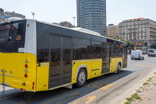 Yellow city bus rides through the streets of the route.