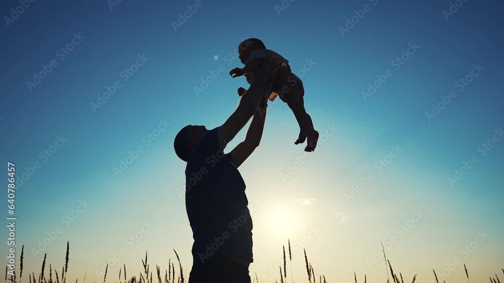 father throws play baby in the park. father's day silhouette happy