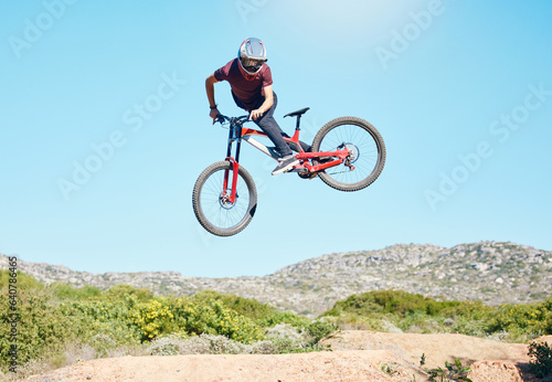 Freedom, air and man cycling in nature training for a sports competition on trail or path on mountain. Action, stunt or cyclist athlete riding bicycle to jump for cardio exercise, fitness or workout photo