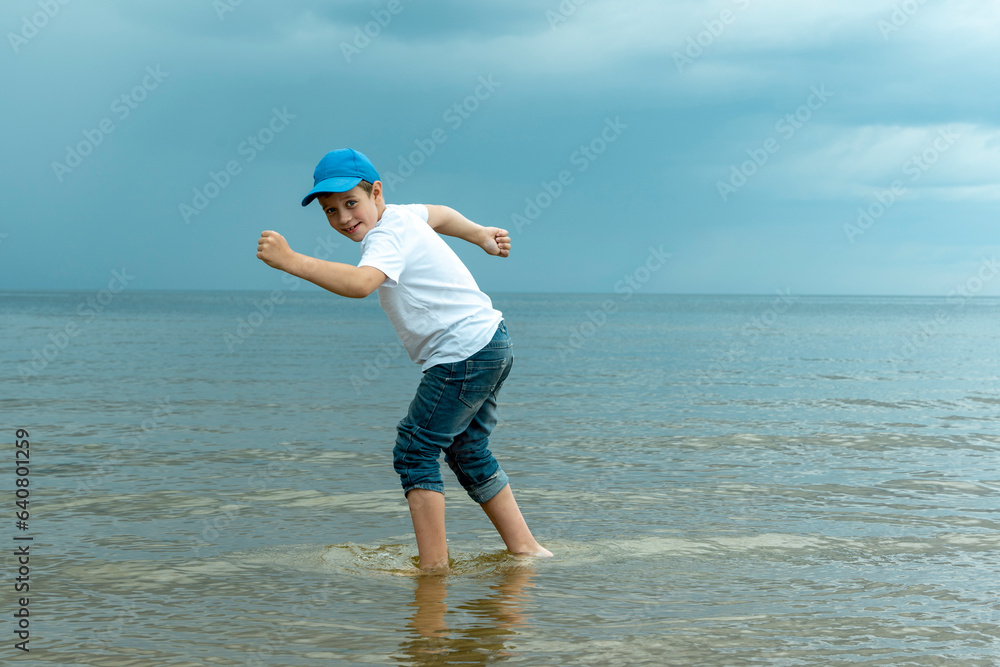 happy boy is standing in the water in the sea and fooling around