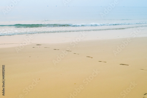 Footprints of human feet on the sand near the water on the beach.