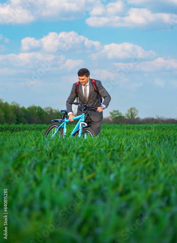 businessman rides a bicycle through a green grass field, the concept of activity, leisure or freelancing © soleg