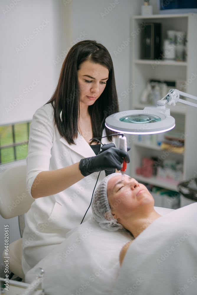 Φωτογραφία Cosmetologist and dermatologist makes injections with a mesotherapy apparatus to a lying woman patient in a beauty salon