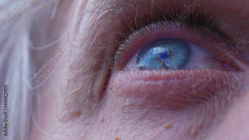 Macro close-up of a senior man's blye eyes staring at clouds in the sky. Extreme detail of person's eye ball looking at sky with HOPE photo