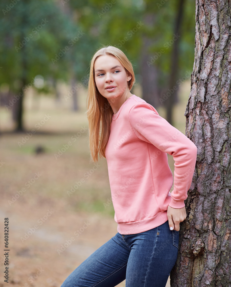 Attractive blue eyed blonde woman walk on the city park. Girl wear pink hoodie, pink bag and look happy and smiles. Attractive blue eyed blonde woman walk on the city park. Girl wear pink hoodie, pink bag and look happy and smiles.