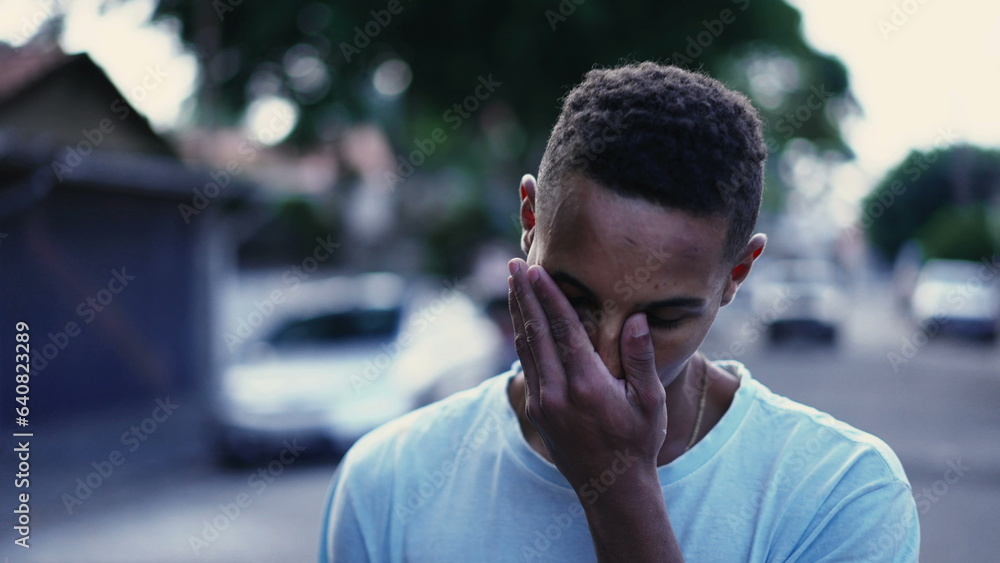 One pensive black man walking forward in street in deep mental reflection and worried emotion. Tracking motion shot of a Brazilian person strolling in urban setting One pensive black man walking forward in street in deep mental reflection and worried emotion. Tracking motion shot of a Brazilian person strolling in urban setting