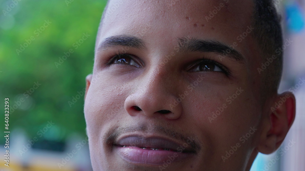 One black Brazilian young man gazing upwards at sky with HOPE and FAITH. Contemplative South American male person with happy expression, looking up close-up face One black Brazilian young man gazing upwards at sky with HOPE and FAITH. Contemplative South American male person with happy expression, looking up close-up face