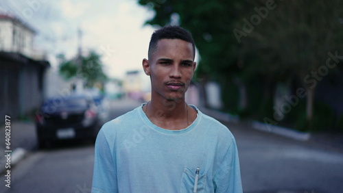 One confident young black man walking forward in street. Close-up face in tracking shot motion of an African Descent person walks outside in urban environment, life's journey concept