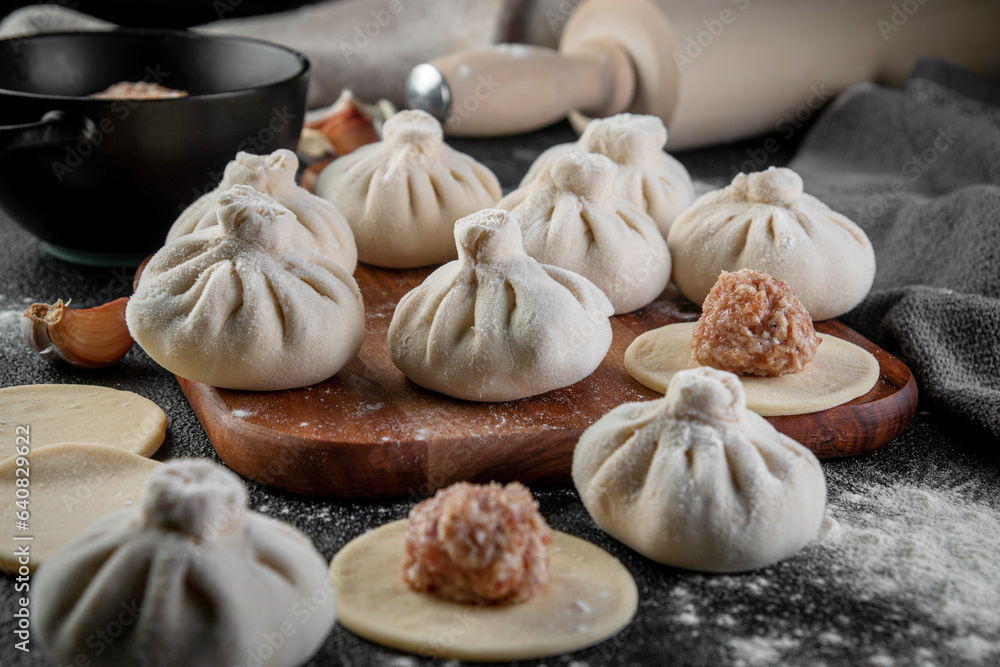 Traditional frozen homemade georgian khinkali or manty dumplings. Ravioli set on a wooden cutting board on a dark table Traditional frozen homemade georgian khinkali or manty dumplings. Ravioli set on a wooden cutting board on a dark table