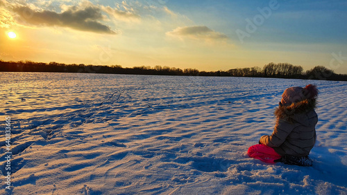 person sitting in snow and watching the sunset