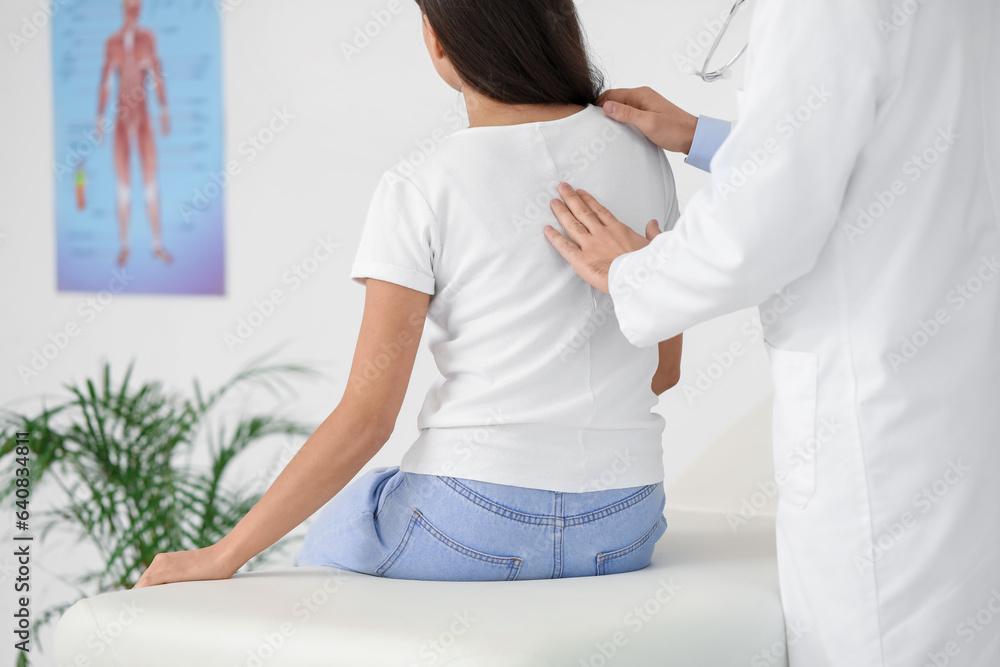 Male doctor checking posture of young woman in clinic Male doctor checking posture of young woman in clinic