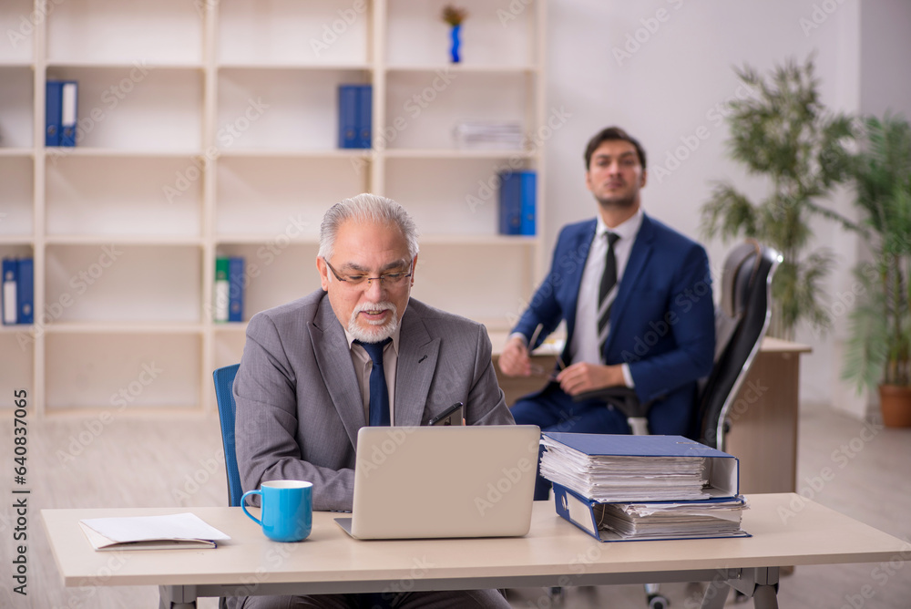 Old male boss and young male employee in the office Old male boss and young male employee in the office