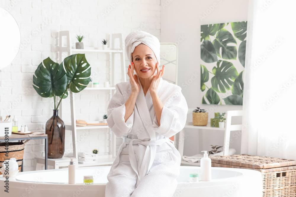 Mature woman applying facial cream in bathroom Mature woman applying facial cream in bathroom