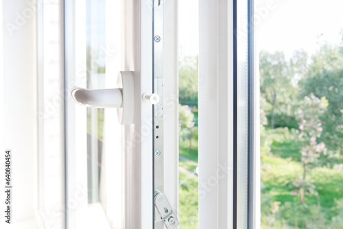 PVC window frame open closeup view. Lock window frame detail. Room open window ventilation. Mechanism of white plastic window sash.